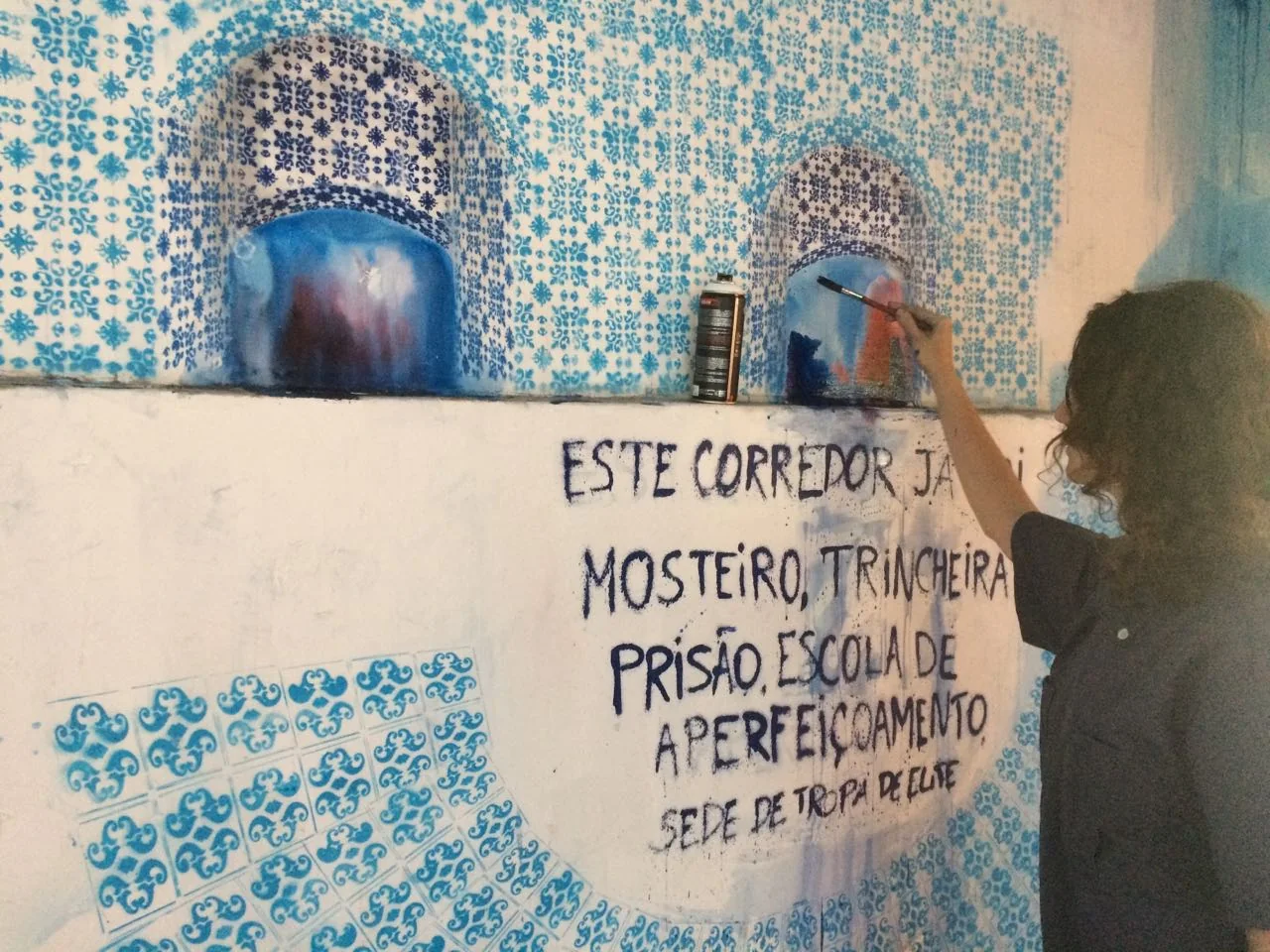 Writing over it: “Este corredor já foi mosteiro, trincheira, prisão, escola de aperfeiçoamento, sede de tropa de elite.” This corridor has already been a monastery, a trench, a prison, a training school, and the headquarters of an elite squad.