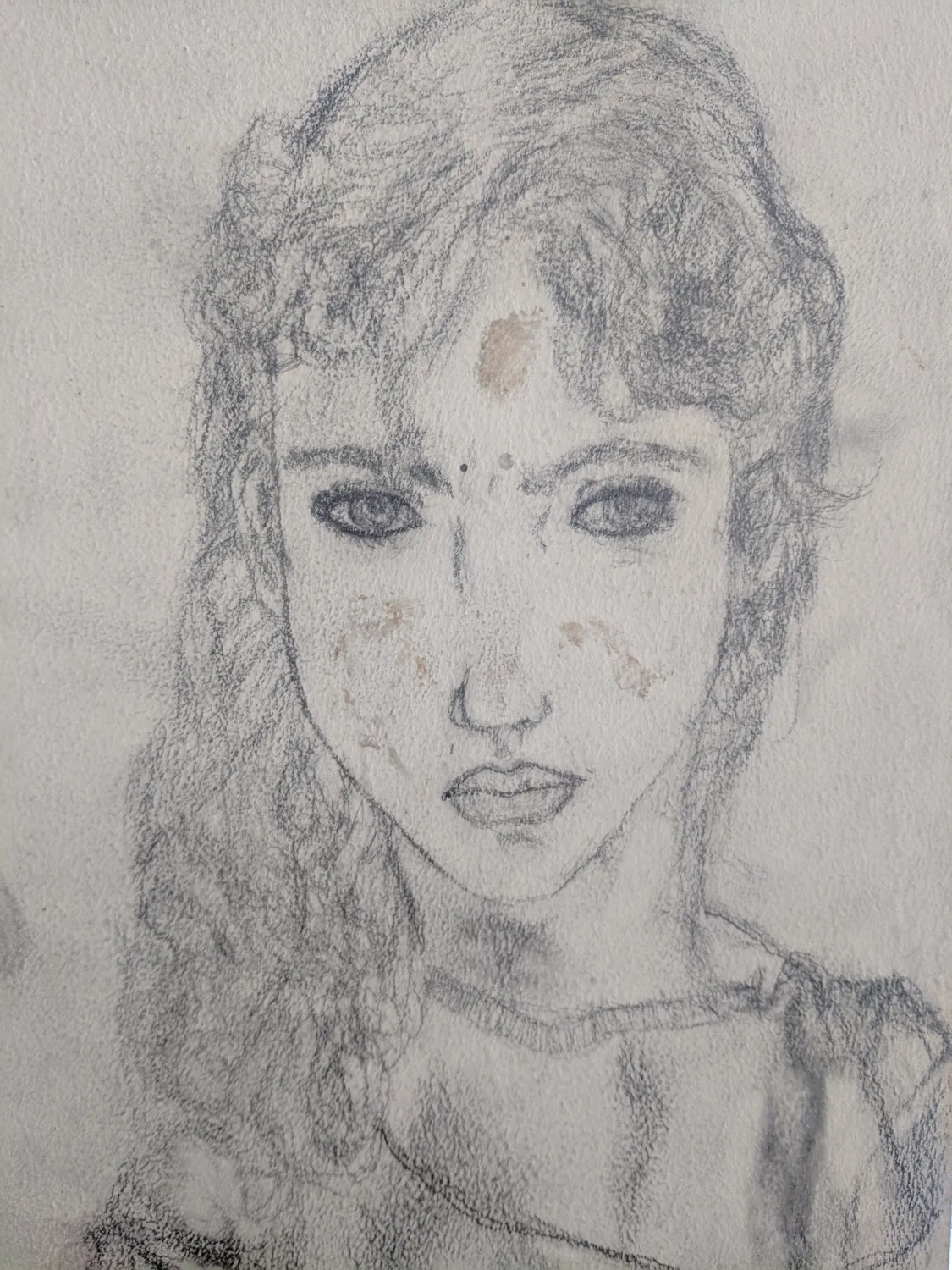 A pencil self portrait on canvas board: a young woman with curly hair looking straight out, drawn in 2000.