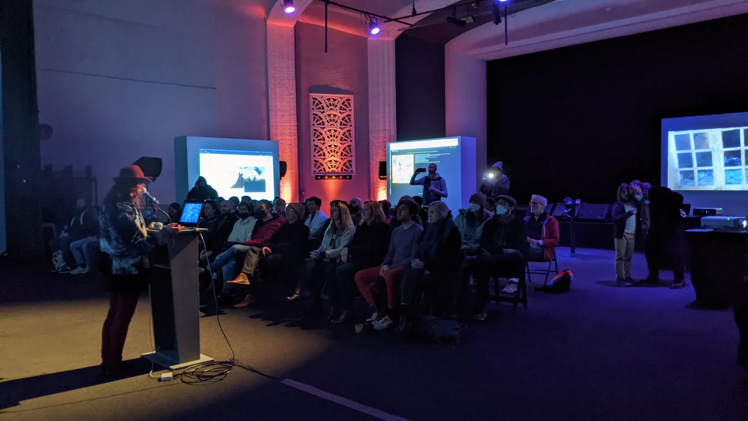 The hall at Gray Area, the audience seated, screens lit on the stage.
