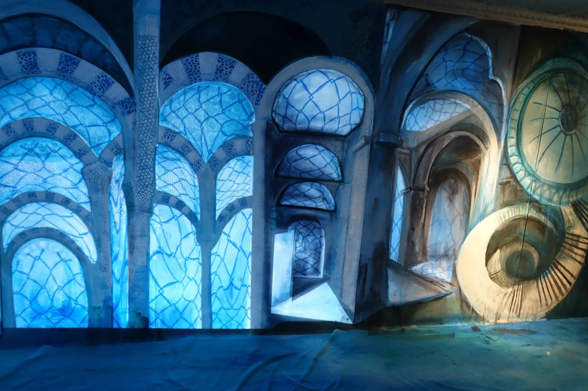 A painted arcade lit blue, arches receding into the dark.
