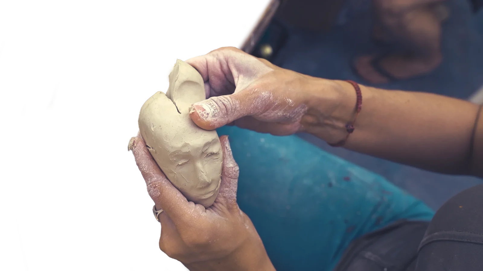 Hands shaping a Little Martian head in clay.