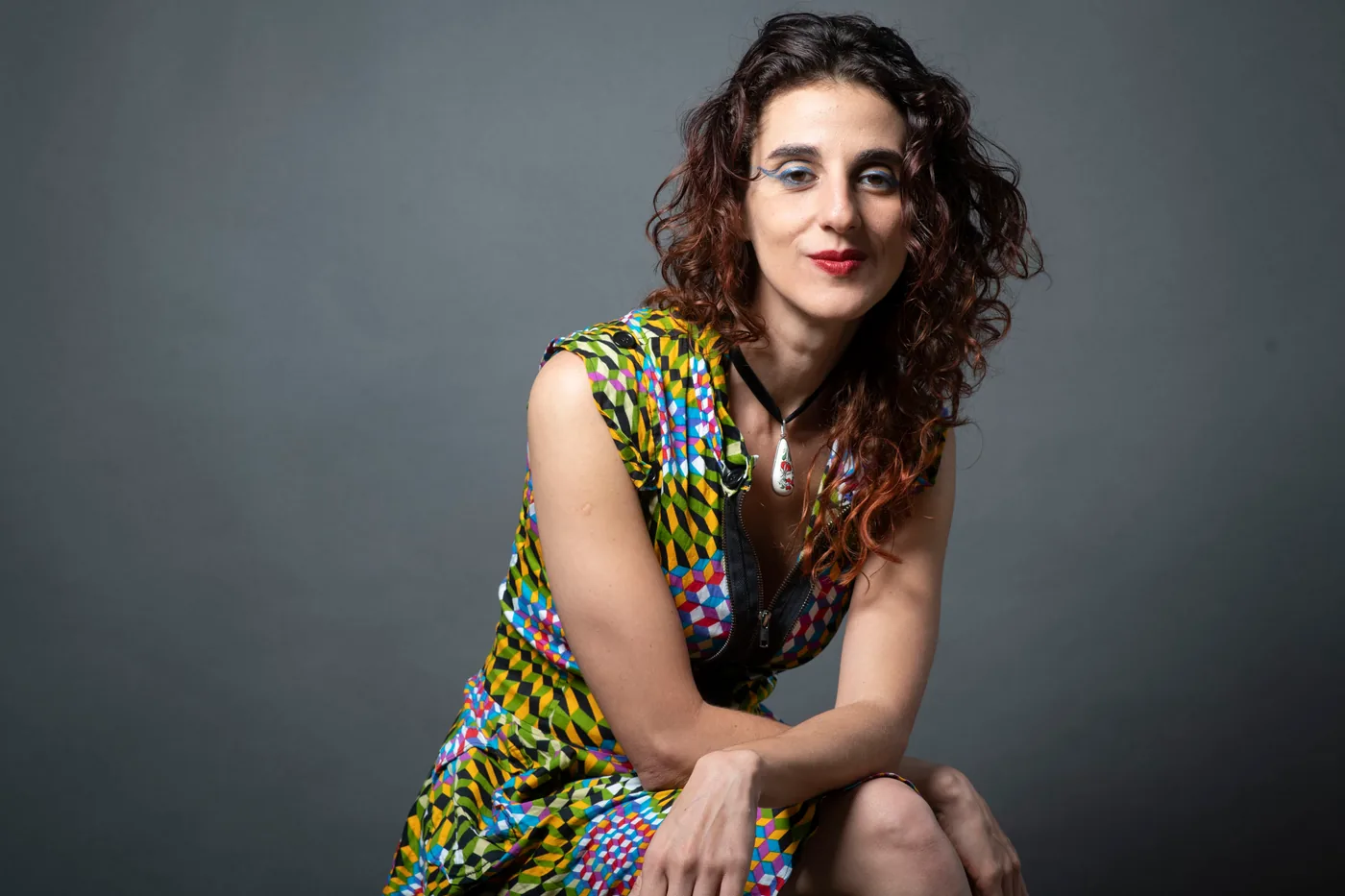 Vanessa Rosa in a patterned dress, against a grey backdrop.