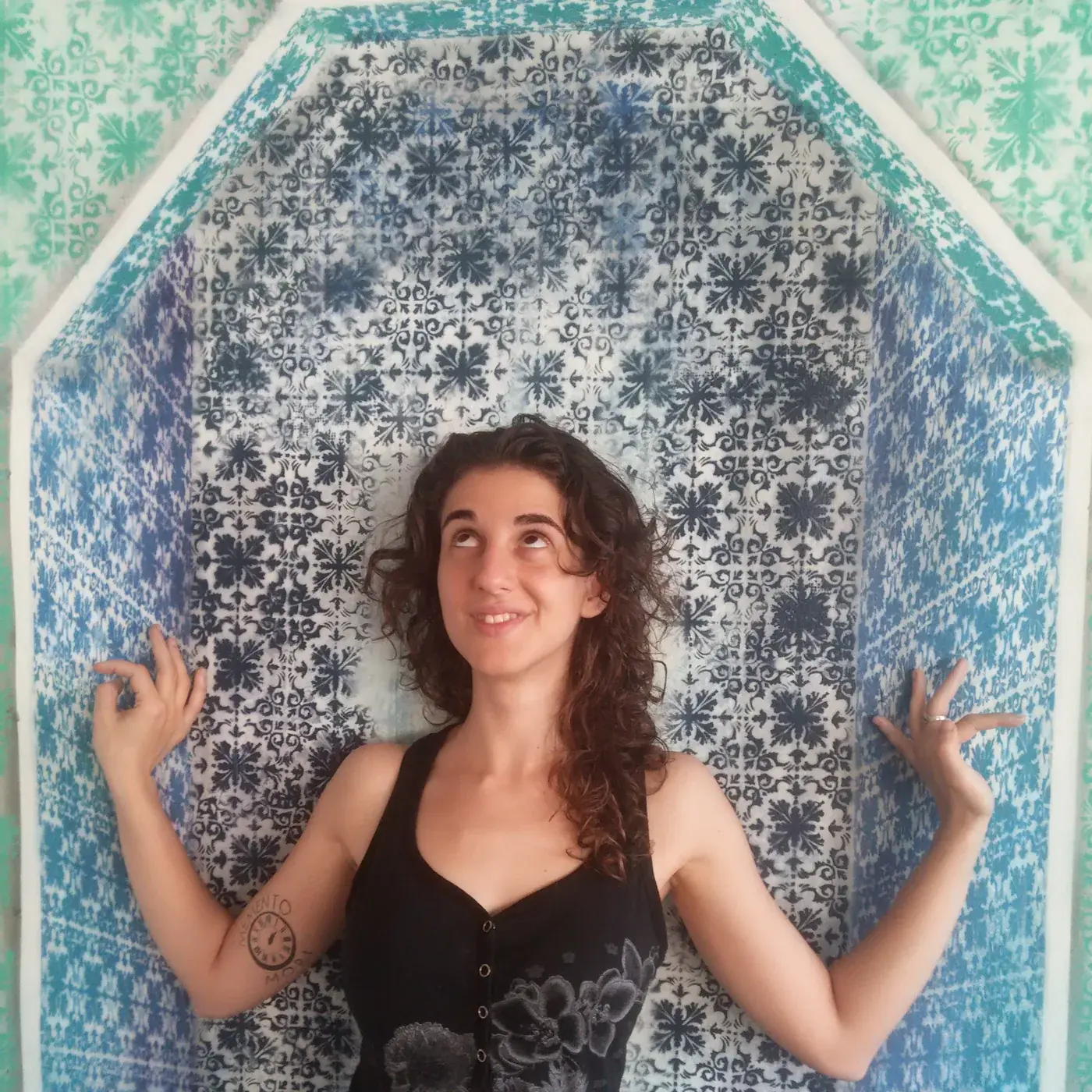 Vanessa Rosa standing in front of a stencilled blue and green tile arch, looking up.