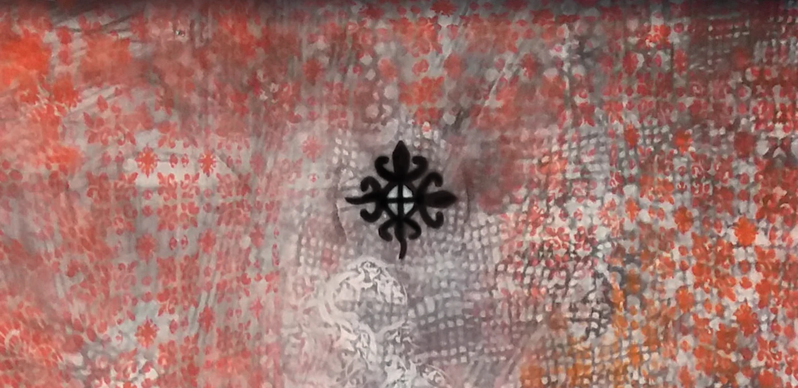 Layered stencilled patterns in red and grey with a black Adinkra symbol at the centre: the cover of the dissertation.